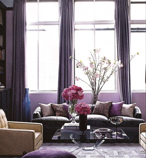 This is an ultra chic living room with the silk pillows, velvet couch and glass coffee table. The floor to ceiling silk drapes create a dramatic backdrop and emphasize the tall ceilings and oversized windows.